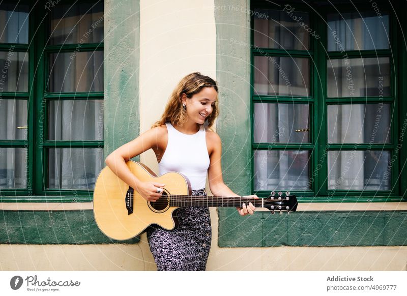 Woman playing guitar in the street woman sitting building music road architecture instrument female musical geometric urban vacation fashion house holiday
