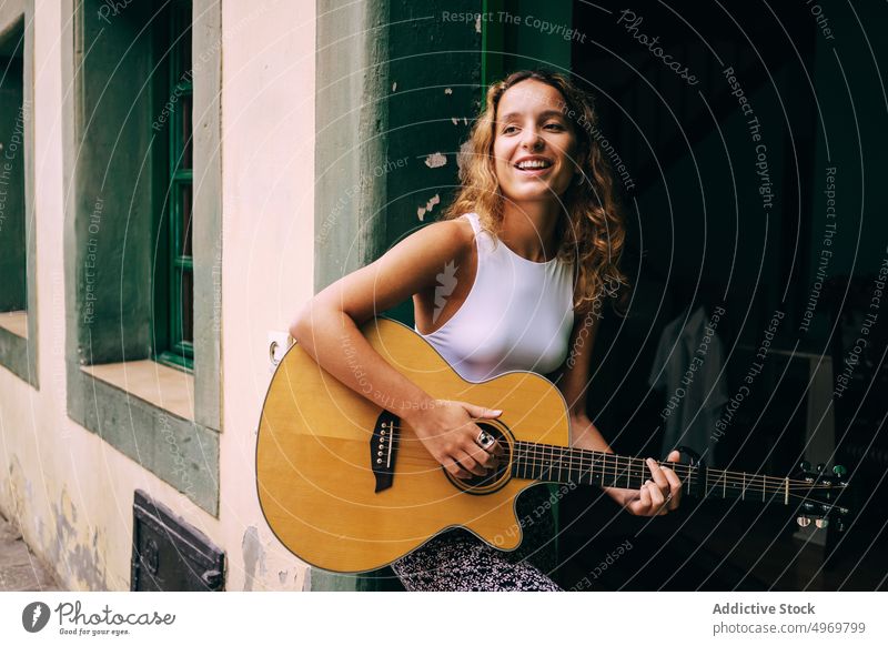 Curly woman playing guitar sitting in a window music romantic young instrument cheerful female musical fun vacation fashion holiday casual summer creative