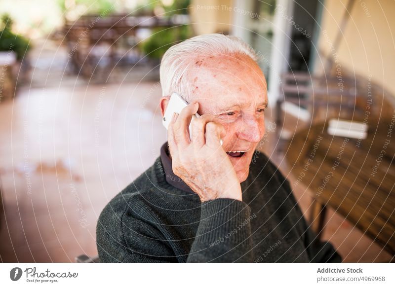 old man using his smart phone lifestyle enjoying isolated candid male emotion up waist person positive adult years gray cheerful holding laughing seniors