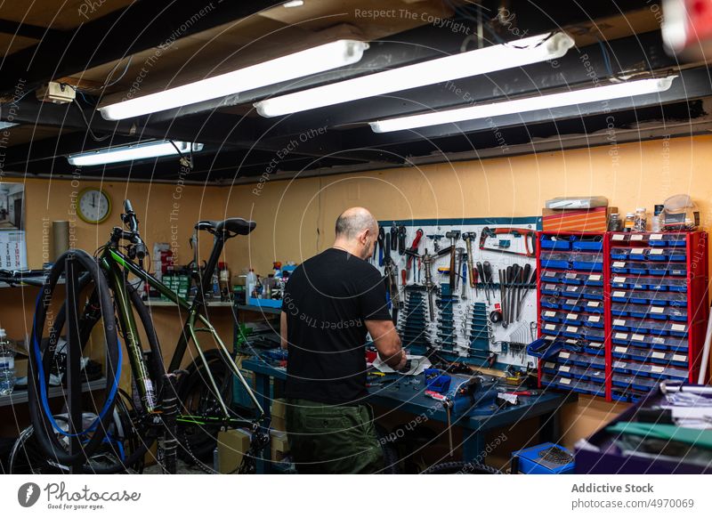 Bald mechanic working in bike workshop bicycle workbench man repair adjustment bald adult service job professional concentrated focused tool check fix