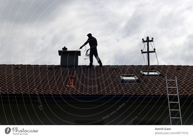 A chimney sweep cleans the chimney on a house roof Chimney sweep Fireside House (Residential Structure) Building Roof Man purge Cleaning Sweep Brush