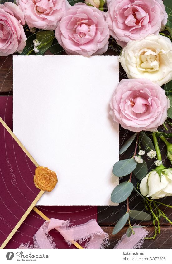 Card and envelope between pink and cream roses on brown wood top view, wedding mockup card flowers rustic Horizontal ribbon silk wooden dark white paper