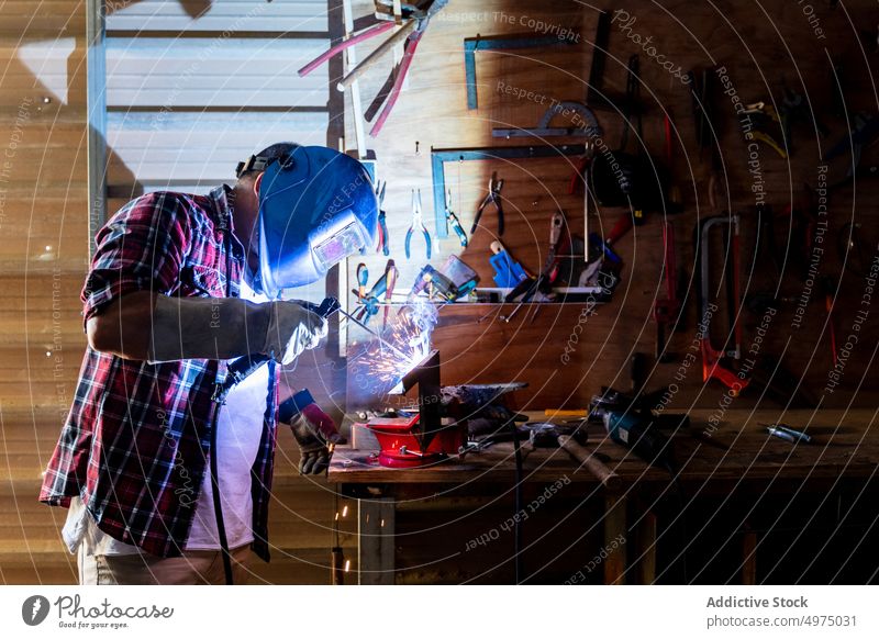 Male cutting piece of metal in modern workshop man angle grinder spark worker equipment using helmet workplace instrument mechanic craftsman process industry