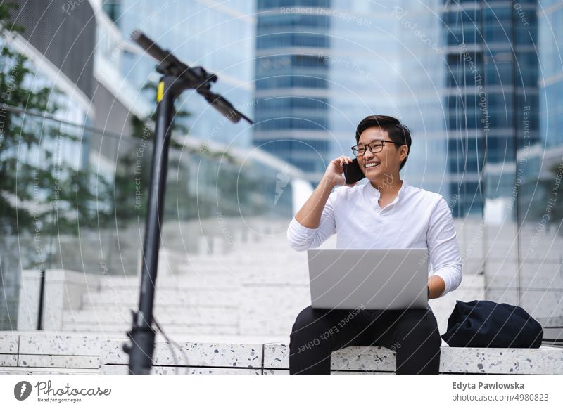 Young businessman sitting outdoors in the city working on laptop real people natural young adult urban student positive smile cheerful career confident