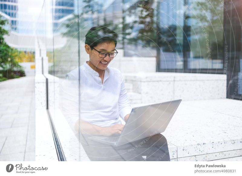 Young businessman sitting outdoors in the city working on laptop real people natural young adult urban student positive smile cheerful career confident