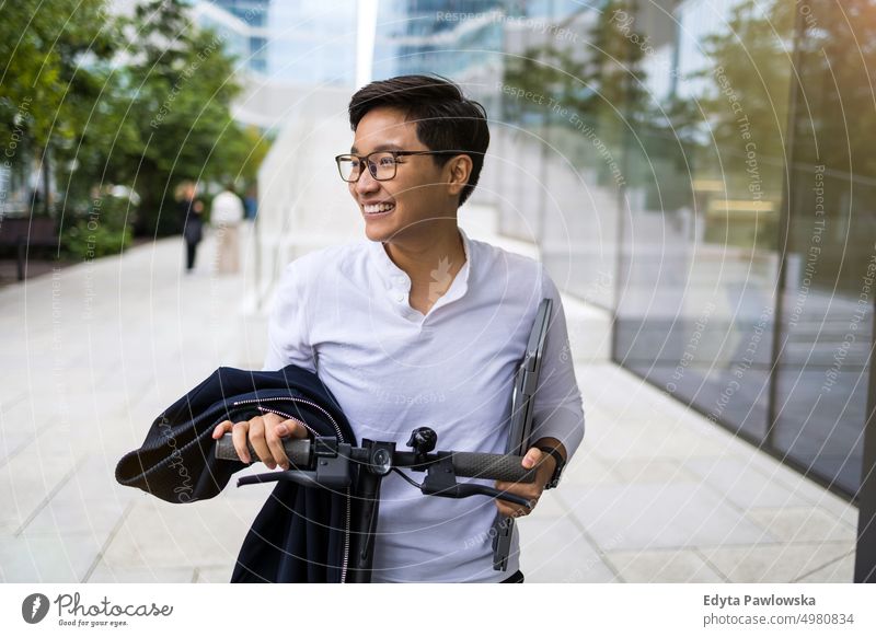 Young man riding electric scooter downtown real people natural young adult city urban student positive smile cheerful career confident successful