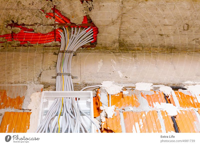 Pile of cables is hanging from a fuse box placed on the wall of unfinished building Block Box Brick Building Site Bundle Cable Circuit Concrete Conductor