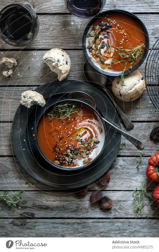 Served soup in bowls on table with vegetable cream tomato served layout seeds apricots wood dried delicious meal bread nutrition buns traditional cutlery