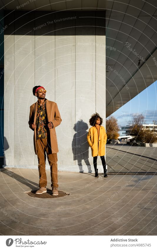 Confident trendy female in coat on street with boyfriend woman fashion colorful couple street style together city ethnic black african american afro exterior