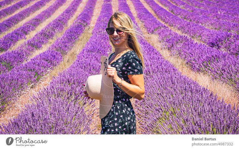 Close up of a young girl in a floral dress with a hat on her head between lavender in southern Provence Valensole France beautiful beauty brunette caucasian