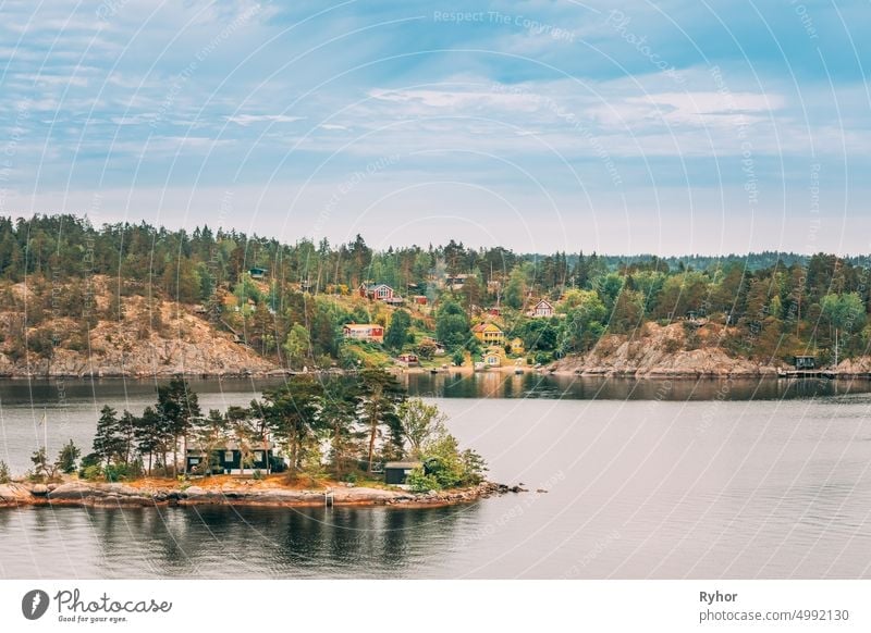 Sweden. Many Beautiful Swedish Wooden Log Cabins Houses On Rocky Island Coast In Summer Day. Lake Or River Landscape apartment archipelago bathhouse beautiful