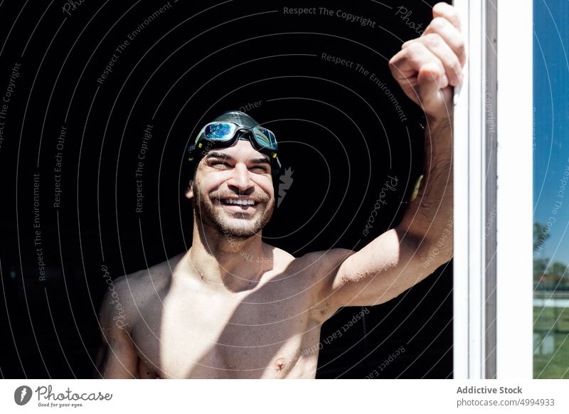 Happy muscular swimmer with naked torso behind window in sunlight athlete happy six pack abs dreamy macho masculine body man portrait smile ponder brutal virile