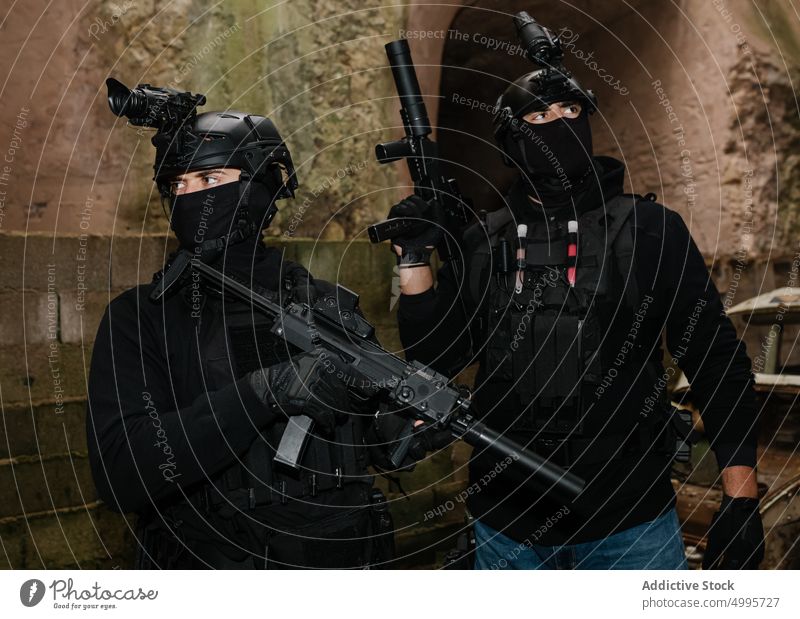 Anonymous squad fighters with rifles aiming near shabby building men combat force protect battle violent danger attack graffiti swat spec ops together gear