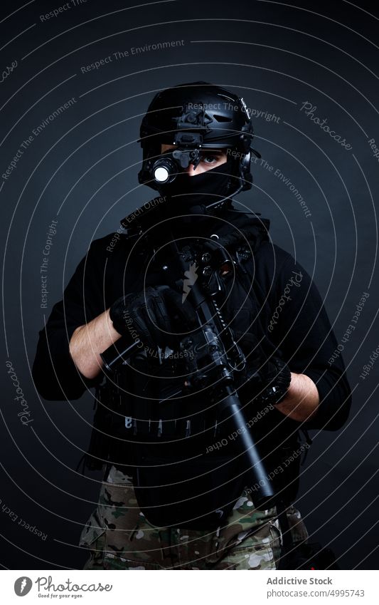 Attentive male warrior with rifle in dark room man combat squad concentrate focus weapon force danger serious fighter professional gear helmet gun safety lens