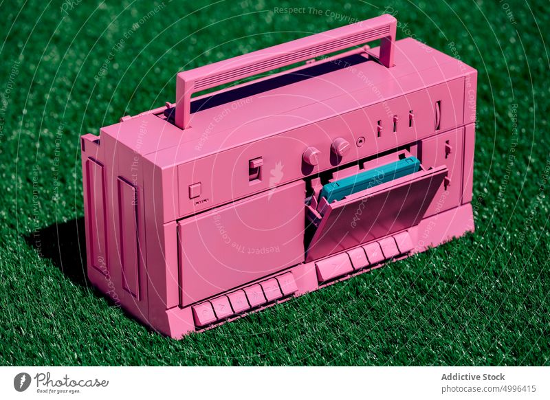 Pink retro tape recorder on grass colorful bright vintage cassette player music stereo old fashioned vivid vibrant audio sound style melody song nostalgia