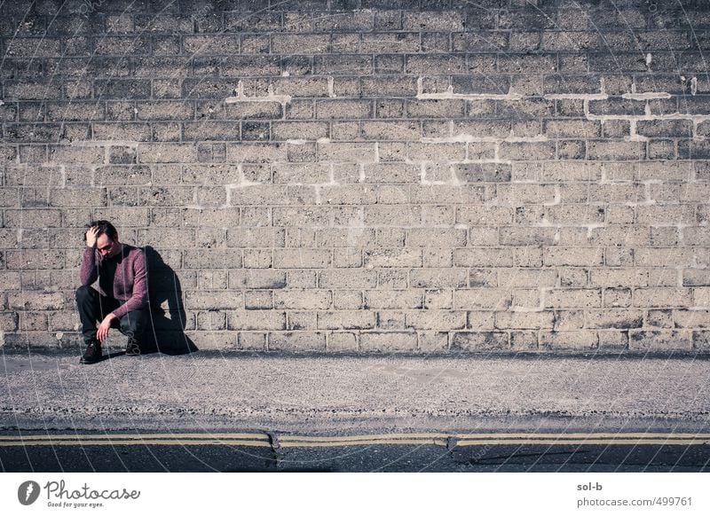 against a wall Unemployment Masculine Young man Youth (Young adults) 1 Human being 18 - 30 years Adults Town Downtown Wall (barrier) Wall (building) Street
