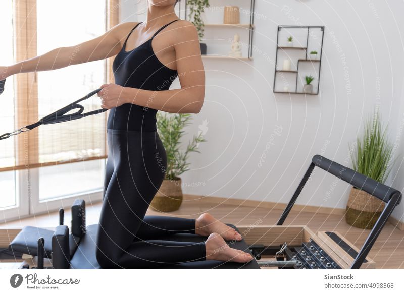 Woman in black workout clothes adjusting reformer bed in a pilates gym  Stock Photo - Alamy