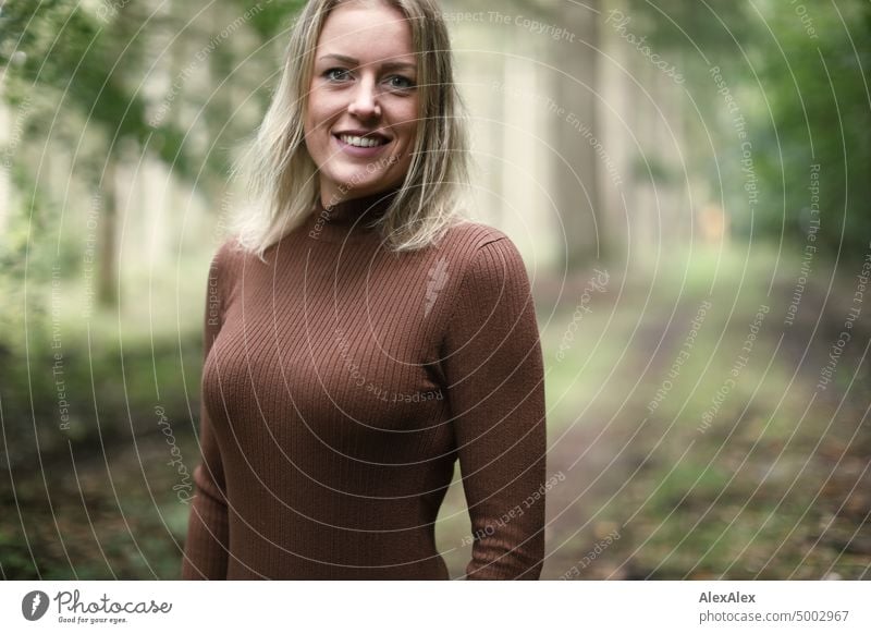 Young blonde woman with dimples stands in forest and smiles happily at camera Young woman Woman Blonde Feminine pretty fortunate Youth (Young adults) portrait