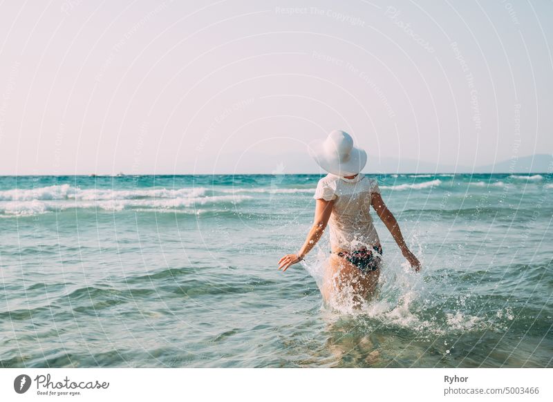 Young caucasian woman woman in swimsuit and summer hat walking in sea. Vacation at sea ocean beach the Aegean splash active active lifestyle Attractive