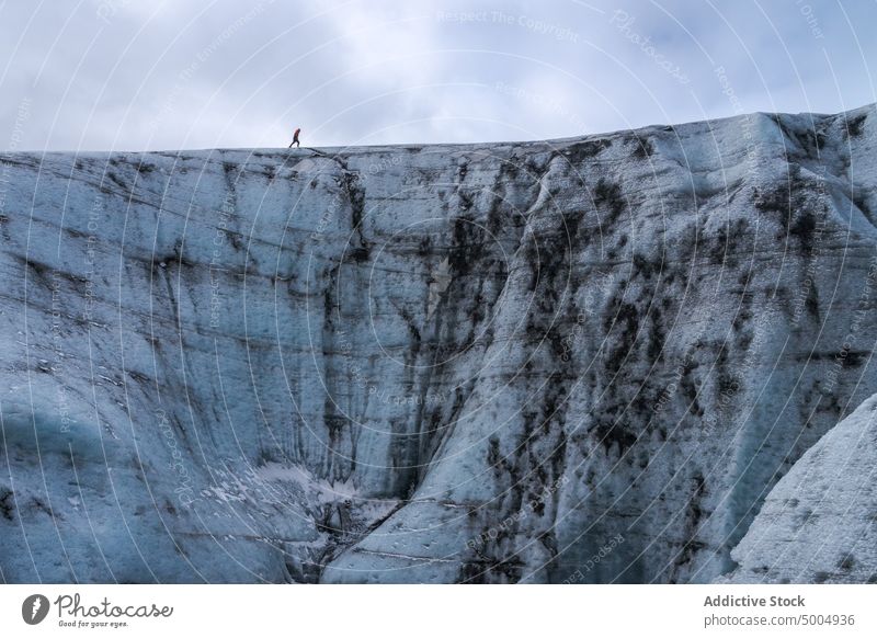 Ice formation with tourist in winter glacier ice traveler cold cloudy sky gray frozen iceland vatnajokull national park climate uneven overcast rough polar