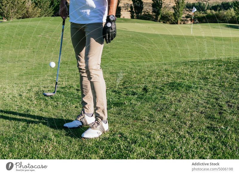 Anonymous sportsman playing golf on sunny day hobby activity lawn ball training club wedge grass field game male casual glove uniform summer nature park active