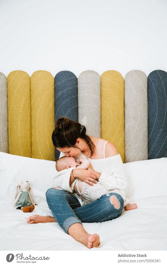 Happy mother feeding tranquil baby while relaxing on bed together at home infant kid parent eat mom harmony child comfort care newborn bedroom love milk