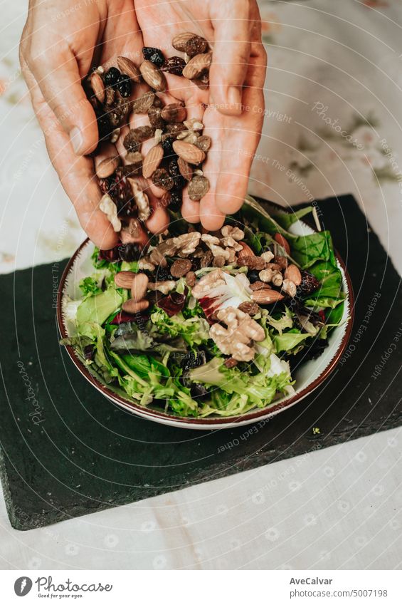 Old woman preparing healthy food, salad recipe on bowl. Preparing vegetables. view of elderly woman's hands stirring the salad with a wooden spoon on the table of the kitchen