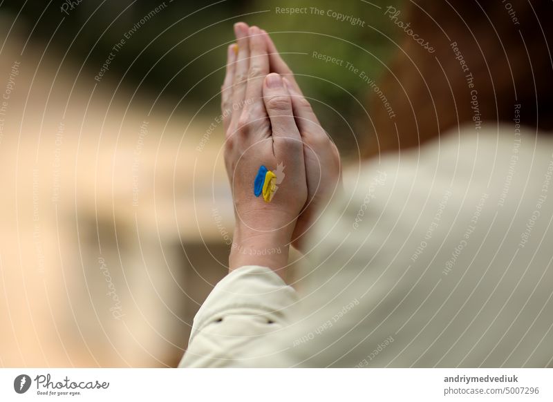 Stop War. Peace in Ukraine. woman hands with picture of flag of ukraine, hands folded in prayer. Antiwar support concept. High quality photo conflict