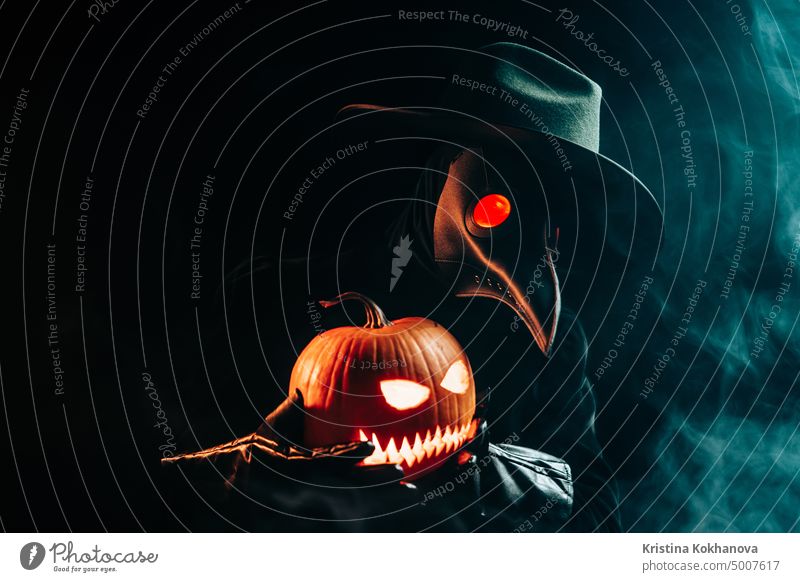 Plague doctor with pumpkin lantern on black smoke background. Creepy raven mask, halloween, historical terrible protection costume, mystical fantasy. plague