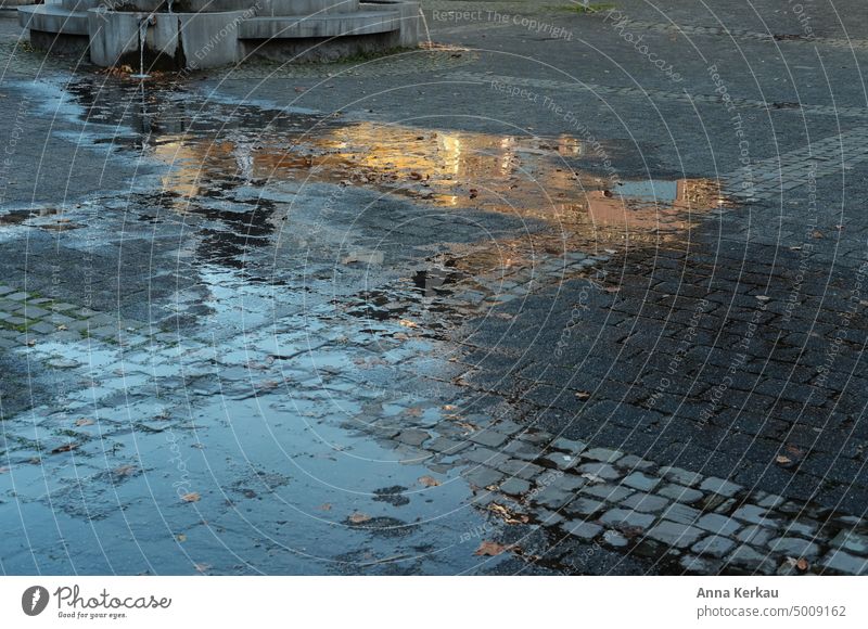 At the golden hour a house is reflected in a puddle on the asphalt reflection Reflection golden light Glittering Reflection in water Reflection in the water