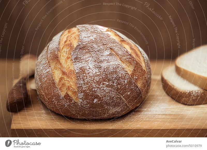 Traditional leavened sourdough bread with rought skin on a rustic wooden table. Healthy food wheat grain loaf nutrition kitchen ferment active white bubble