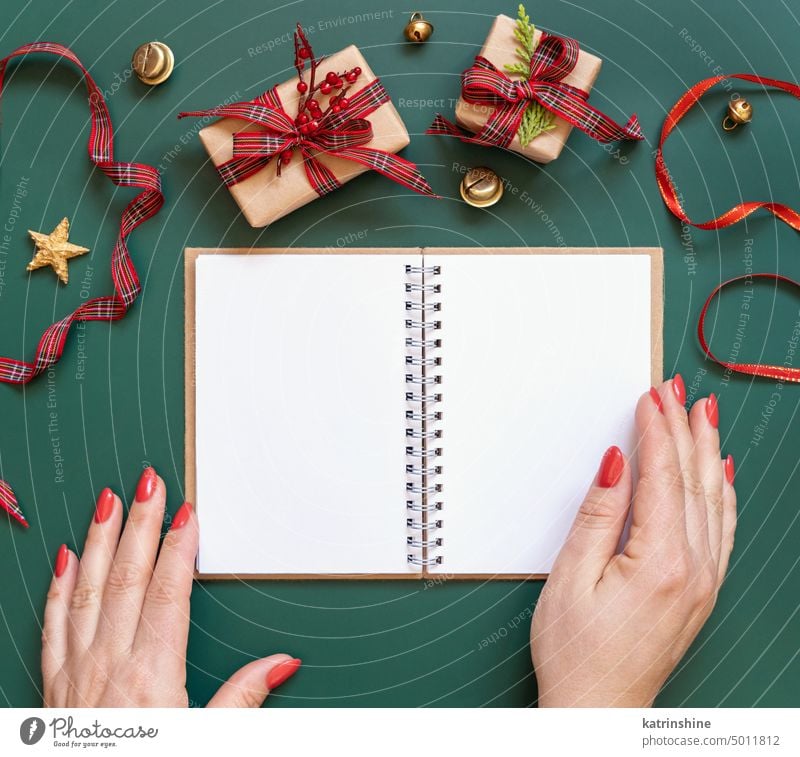 Hands with Blank open notepad on a green background near Christmas presents, mockup opened hands gift box ornaments white blank copy space red planning new Year