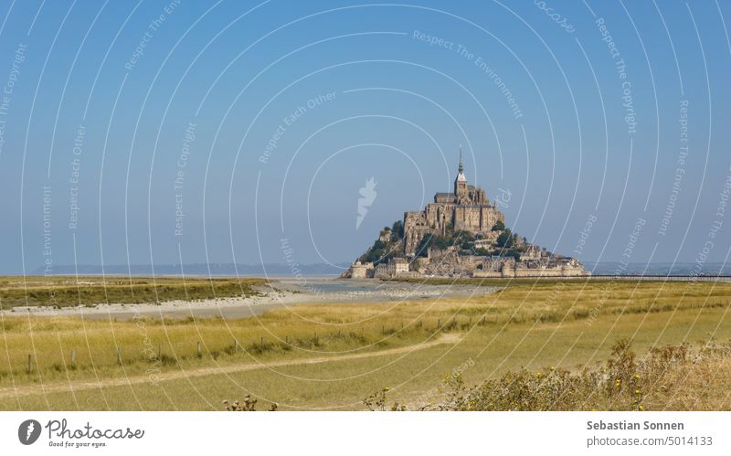Beautiful view of famous historical tidal island Le Mont Saint-Michel with meadow landscape in foreground, Normandy, France Ocean abbey Town travel Castle