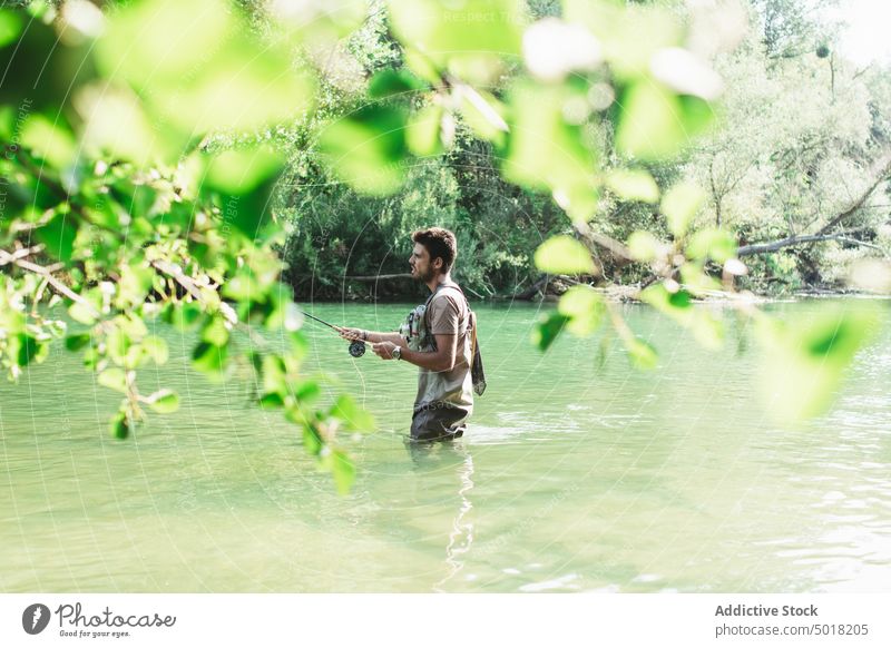 A Man Fisherman On The River Throws A Fishing Pole Stock Photo