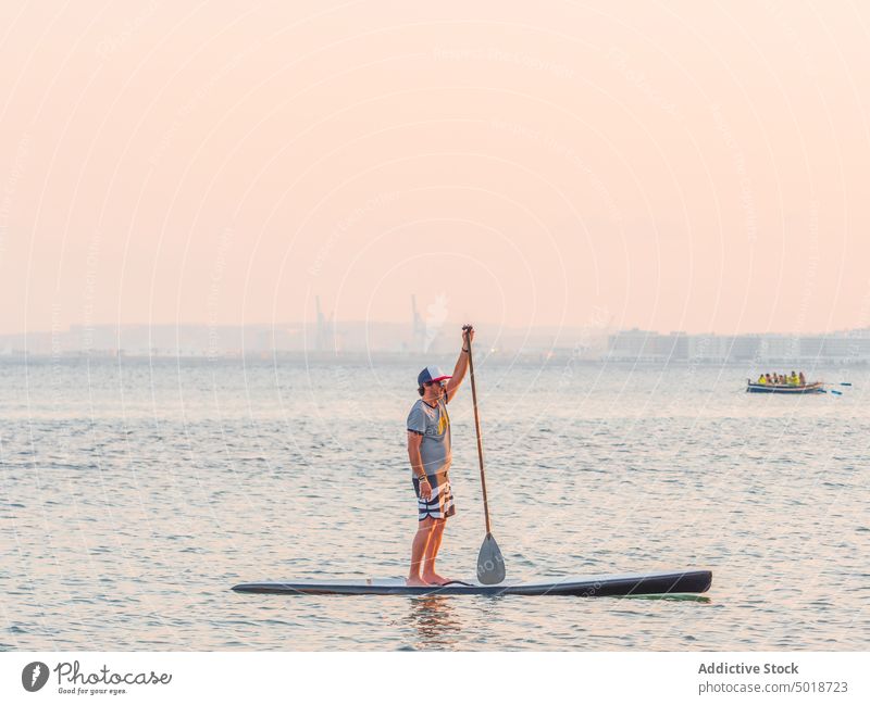 Man with paddle on surfboard on high seas man surfing ocean water active vacation summer male lifestyle extreme wave adventure recreation athlete summertime