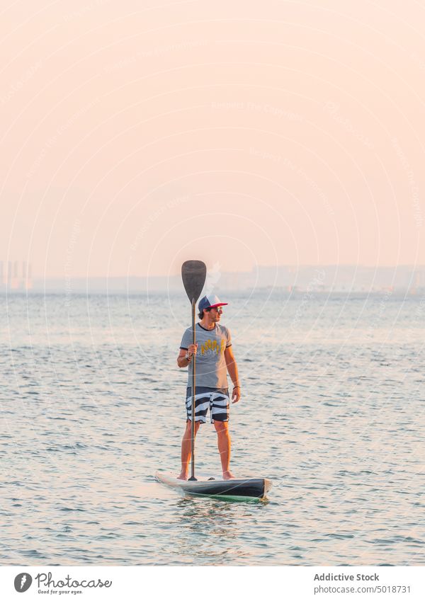 Man with paddle on surfboard on high seas man surfing ocean water active vacation summer male lifestyle extreme wave adventure recreation athlete summertime