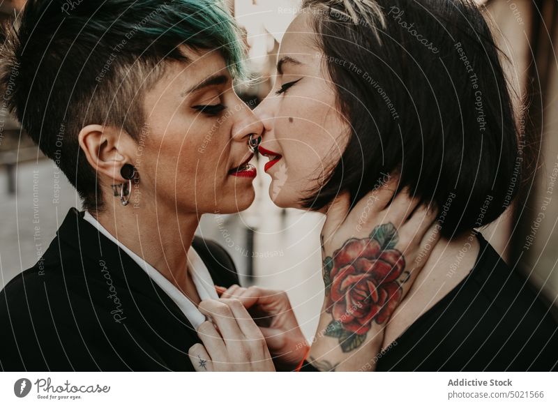 Young stylish ladies kissing on street lesbian couple piercing tattoo love young romantic relationship female adult girlfriend closed eyes lifestyle lovers