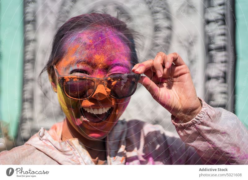 Positive woman with face in Holi powder holi cheerful festival hindu street celebrate colorful having fun paint female india event sunny tradition culture happy