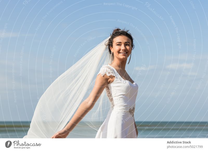 Smiling bride in elegant dress on sandy sea shore white dress happy woman cheerful style feminine wedding content celebrate veil seashore smile delight festive