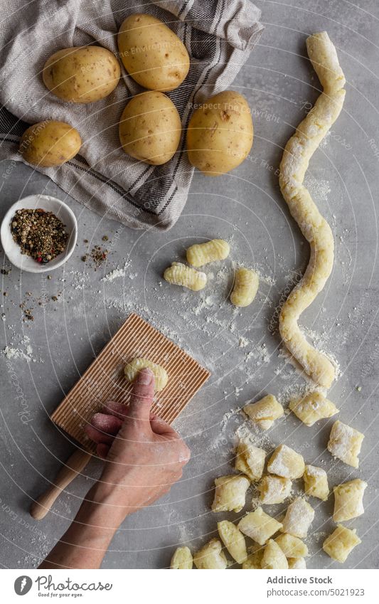 Crop person cooking potato gnocchi for lunch dough press board ribbed pasta table kitchen pepper flour prepare food ingredient process fresh recipe cuisine raw