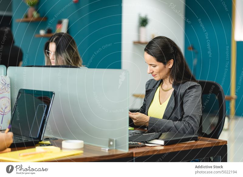 Focused ethnic woman sitting at table with laptop during work in office entrepreneur project using busy concentrate female hispanic occupation focus serious