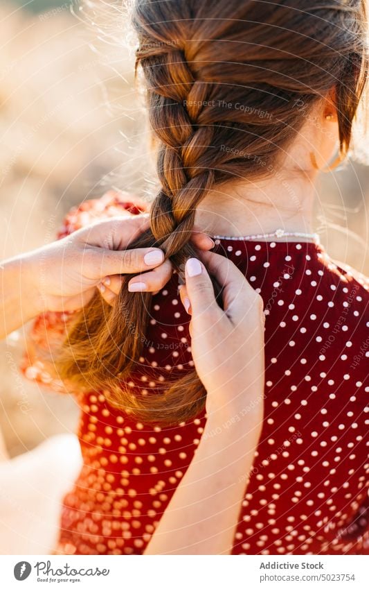 Women braiding hair sitting on rocky cliff on mountain peak women friend hairstyle hilltop female ground nature spend time casual stone summer slope spare time