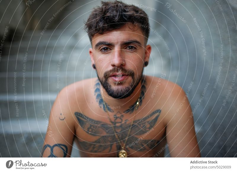 Pensive shirtless young man with tattooed body serious step beard hipster cool model pensive thoughtful contemplate modern fashion handsome relax alone unusual