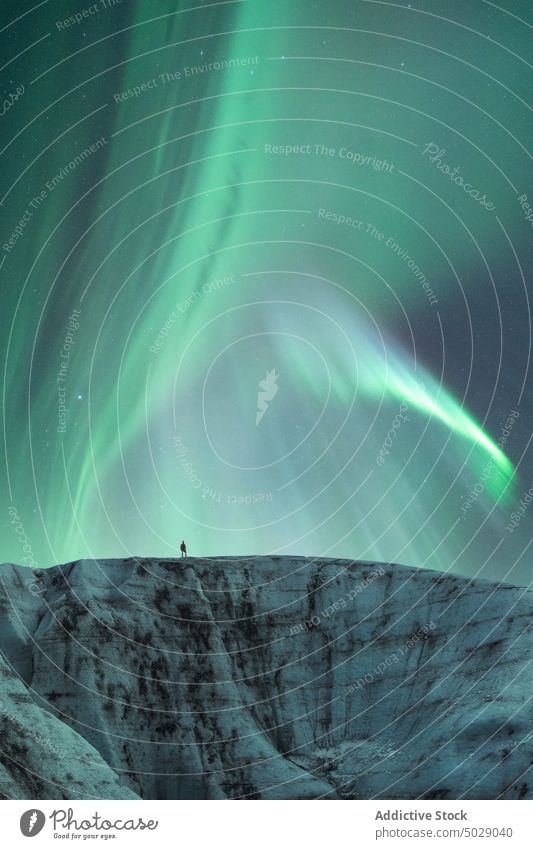 Traveler against night sky with glowing polar lights aurora borealis glacier northern ice formation traveler winter cold frozen iceland vatnajokull green