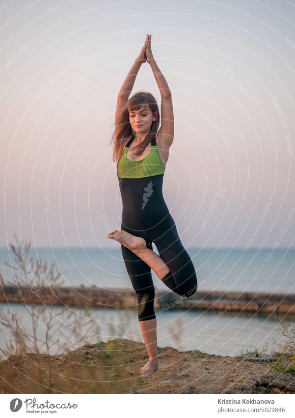 young woman in swimsuit practicing yoga at amazing sunrise. Fitness, sport, yoga and healthy lifestyle concept. Girl doing a bridge on rock in sea. nature