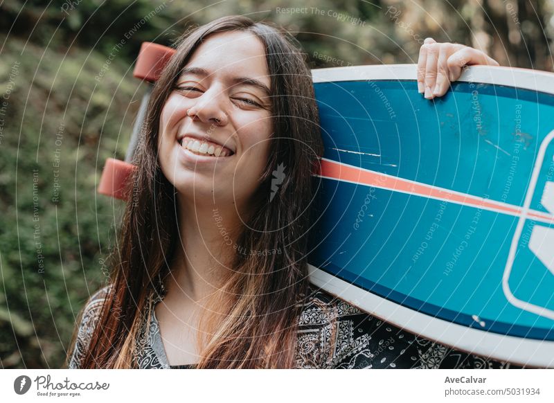 Young woman posing and smiling with a skateboard.Longboarding in the forest, Gen Z sport activities teenage smile person portrait young nature beautiful