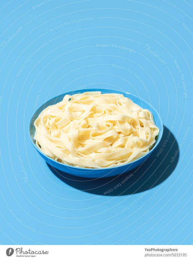 Tagliatelle noodles without sauce in a blue bowl above background boiled bright carbs classic color cooked copy space creative cuisine cut out delicious dinner
