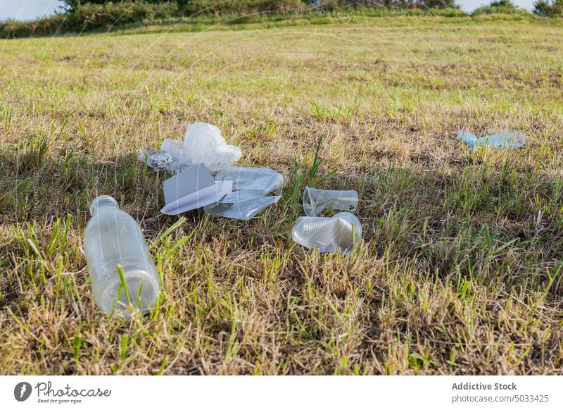 Plastic trash left on grassy ground waste plastic bottle cup foil pollute used meadow rubbish environment container ecology nature litter garbage disposable