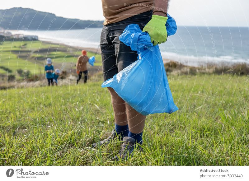 Unrecognizable man standing on nature with trash bag volunteer collect litter environment ecology daytime garbage bin rubbish waste sun activist recycle clean