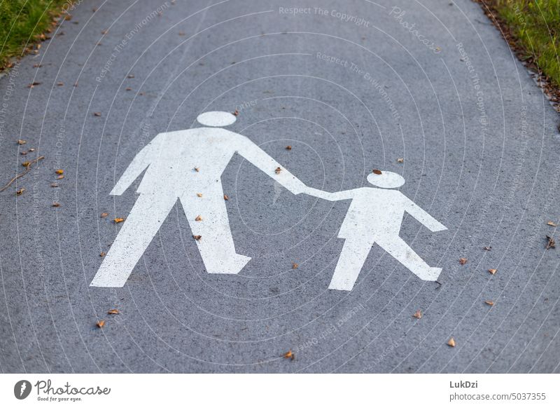 Adult and child holding hands sign on a pavement Road safety Asphalt Zebra crossing Pedestrian crossing Traffic infrastructure crossing the street concept